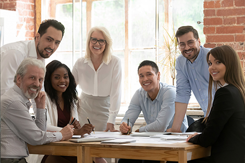 Professional business team young and old people posing together at office table, happy diverse leaders employees looking at camera, smiling multiracial staff corporate people workers group portrait