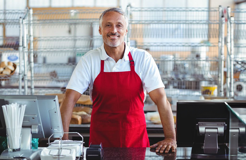 Barista smiling at camera behind counter in the bakery