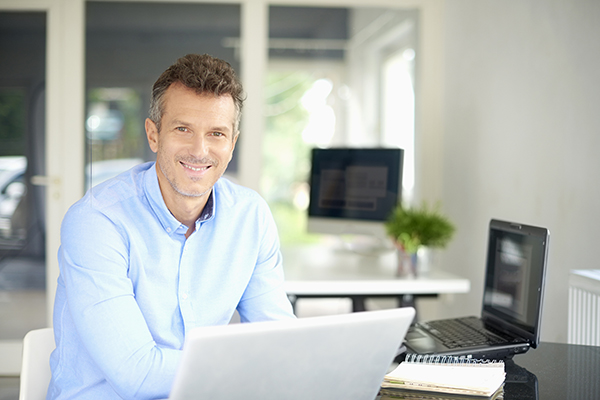 Happy businessman wearing shirt while sitting at office desk and using his computer.